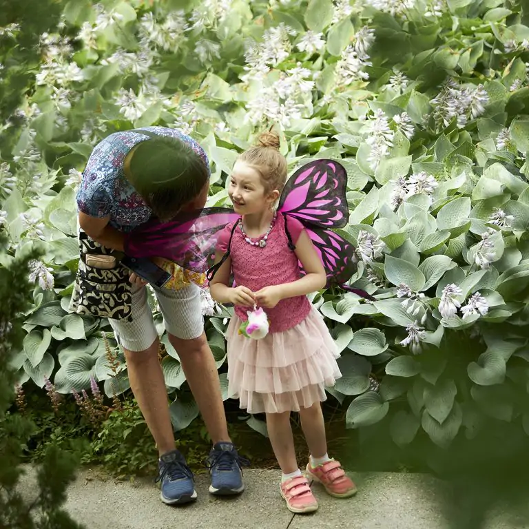 child dressed as a fairy standing with an adult in a garden