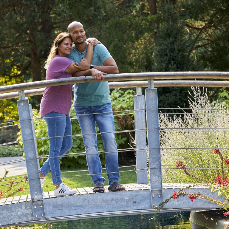 couple leaning together in embrace on a footbridge and looking around the Rock Garden