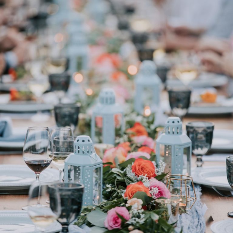 long community table deorated with roses, greenery, and lanterns.