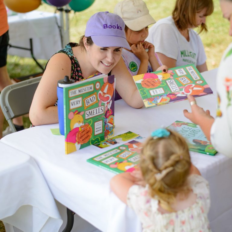 author signing a book for a young child. The book is titled, 