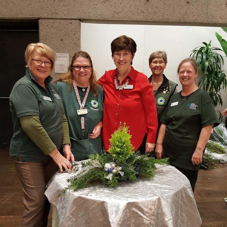 Workshop volunteers with an evergreen arrangement