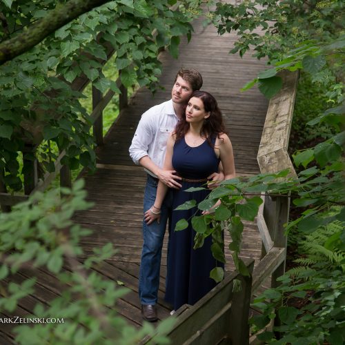Couple-posing-on-boardwalk-in-woodland-garden Couple Posing On Boardwalk In Woodland Garden