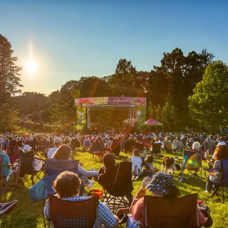 Outdoor concert in the gardens on an open stage decorated with plants