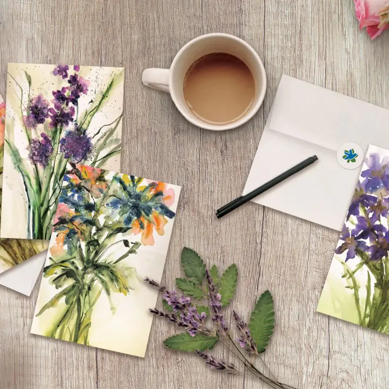 set of floral watercolour notecards laid flat on a desk with flowers and a cup of coffee