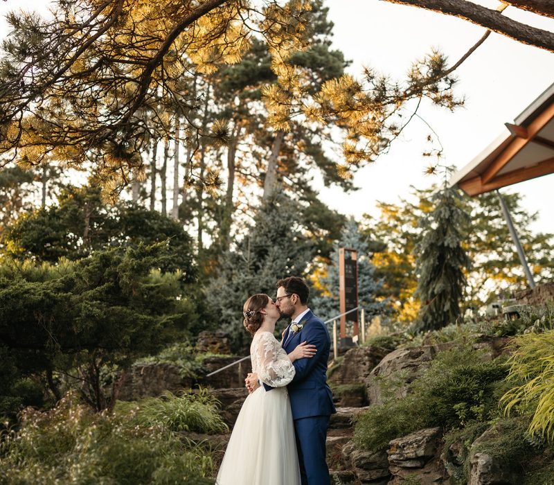 2023_Wedding_rock_GeoffShaw_05629 Bride and groom embracing along limestone steps in a summer rock garden wedding venue