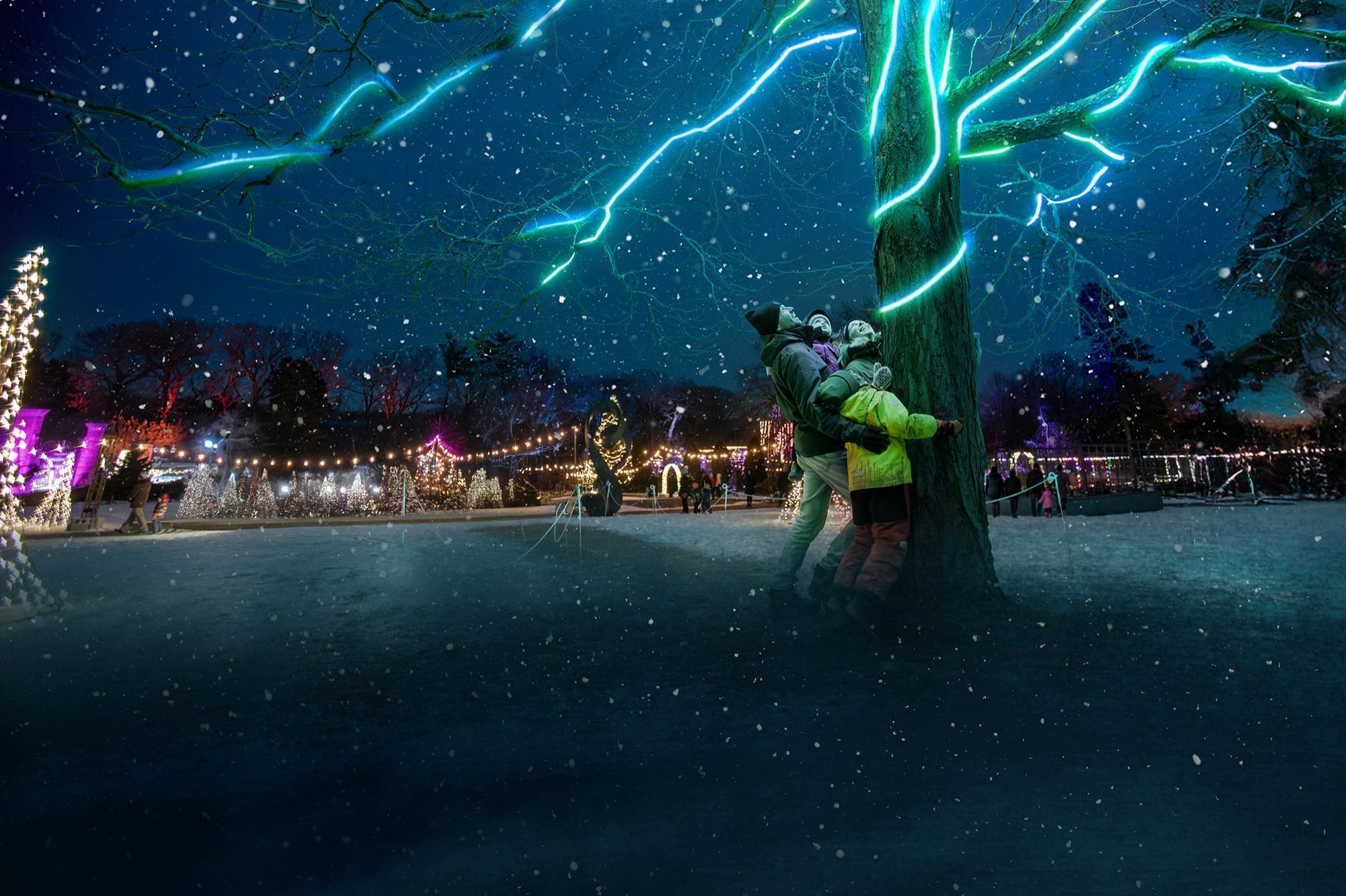 Family hugging a tree lit with lights, with HendriePark lit for Winter Wonders in the background