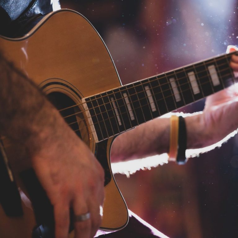 Hands playing an acoustic guitar in evening lighting