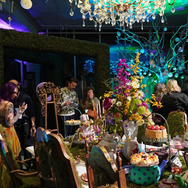 Group around a display of the Mad Hatter Tea Party during RBG After Dark