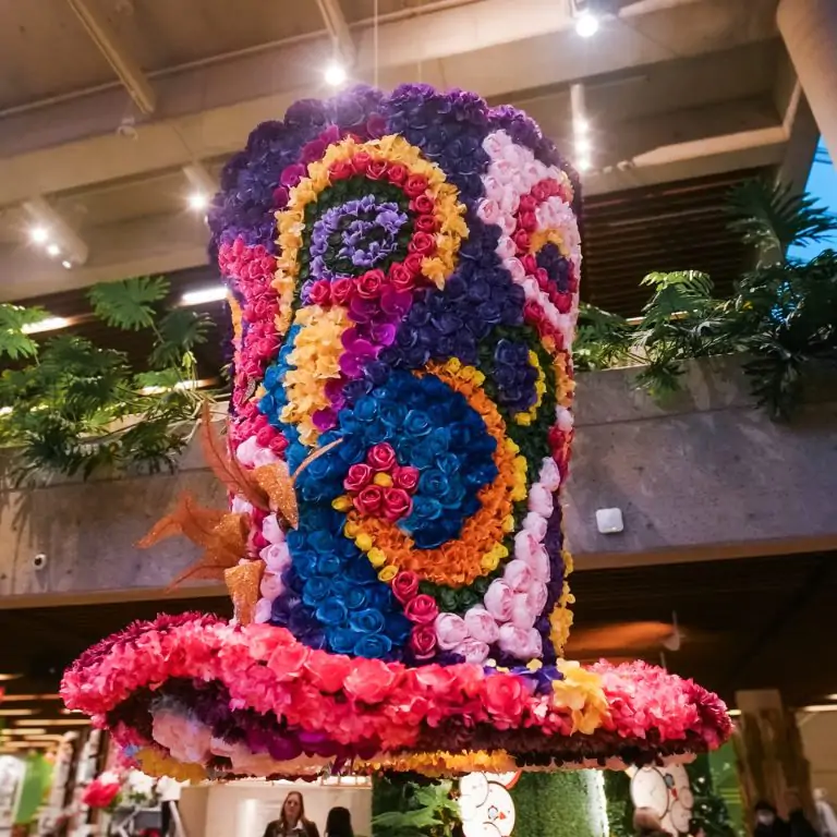 giant top hat made out of vibrant flowers in a whimsical pattern hanging from tall ceiling