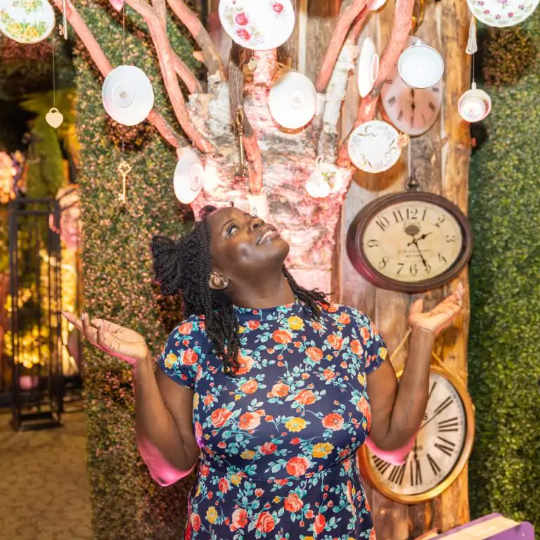 woman looking up towards tea cups strung from tree branches