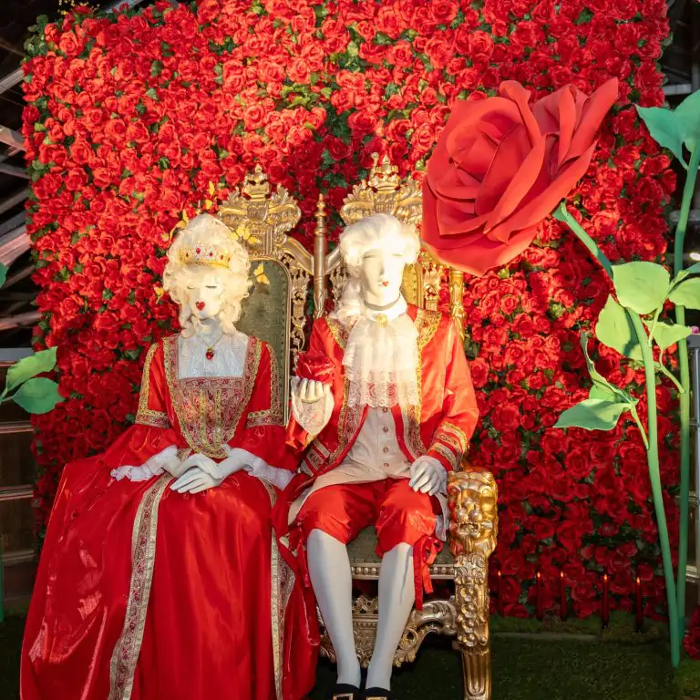 Queen and King of Hearts mannequins sitting on a throne surrounded by red roses