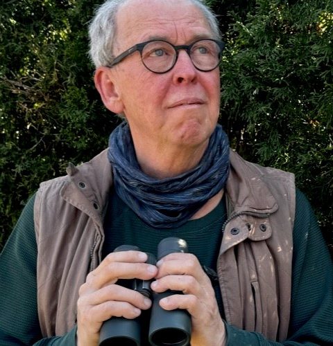 Barry Coombs in nature, holding a pair of binoculars