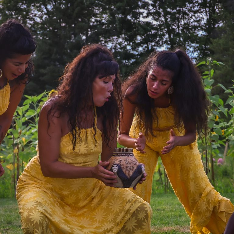 Indigenous dancers performing in a ring of sunflowers, holding a Skybeings Pot