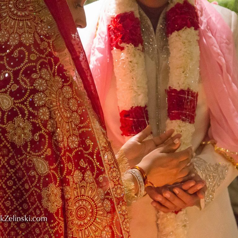 Bride and groom standing close and putting their hands together in Hindu ceremony