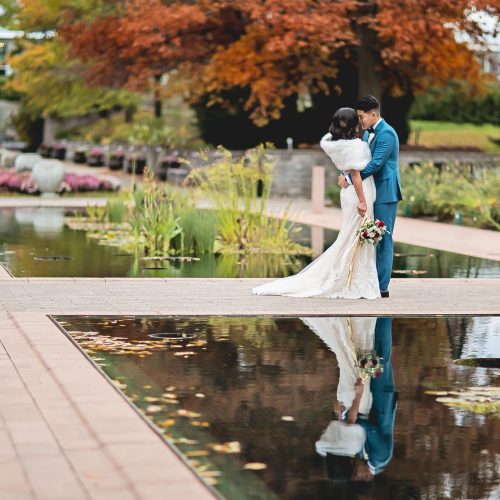 Bride-and-groom-kissing-near-reflecting-pool Bride and groom embracing at the edge of reflecting ponds, in fall