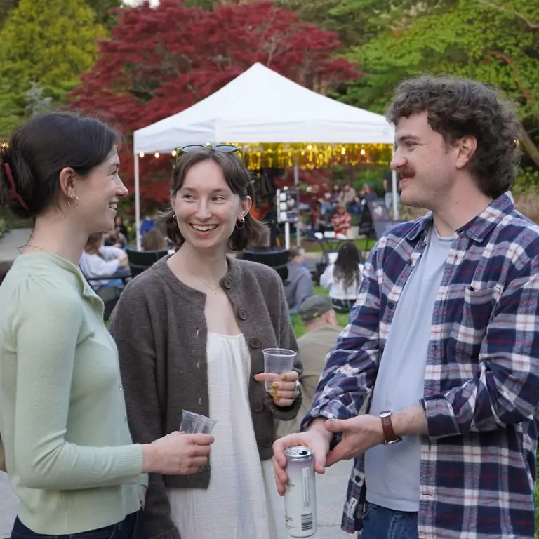 visitors in their 20's with drinks chatting in the Rock Garden at night