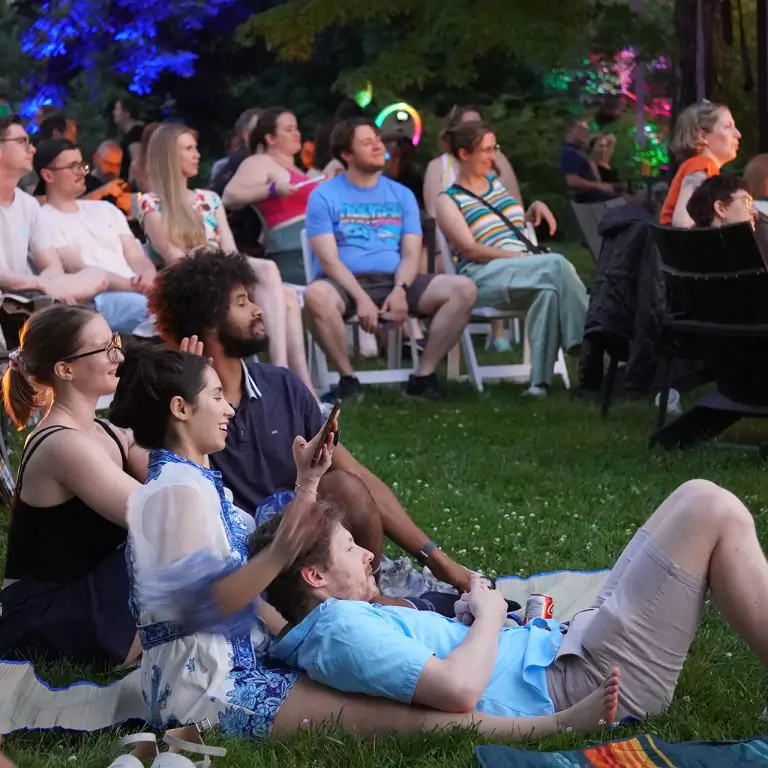 group of adult visitors lounging on the rock garden lawn watching a performance