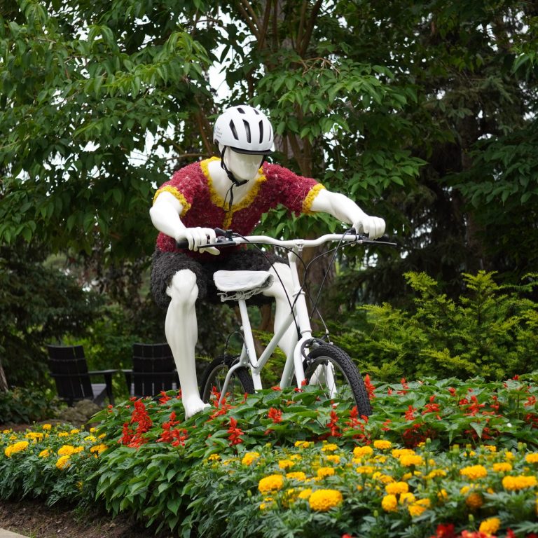 mannequin posed as a cyclist at the centre of a vibrant floral bed. The cyclist is wearing an outfit made out of coloured moss.