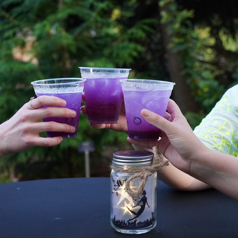 Three hands clinking glasses with purple drinks