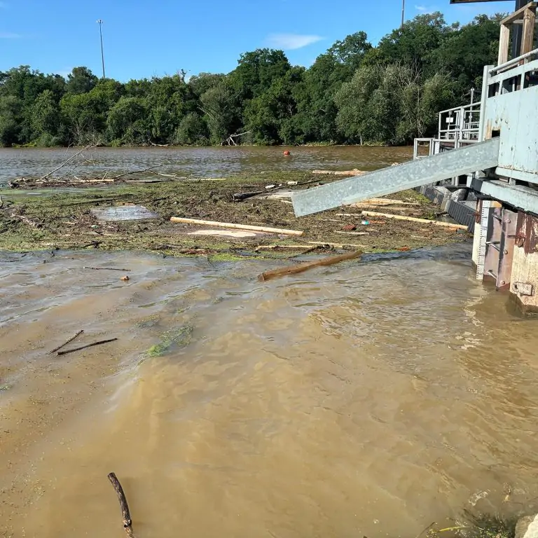 brown water and debris surrounding fishway after flooding