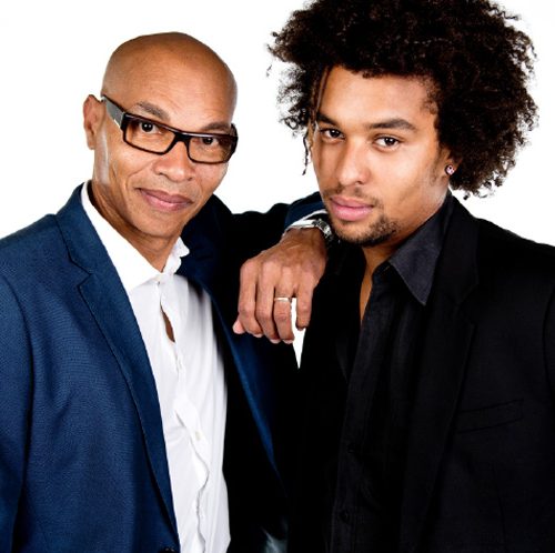 Eddie and Quincy Dueling Pianos Two men in fashionable suits pose for the camera on white background