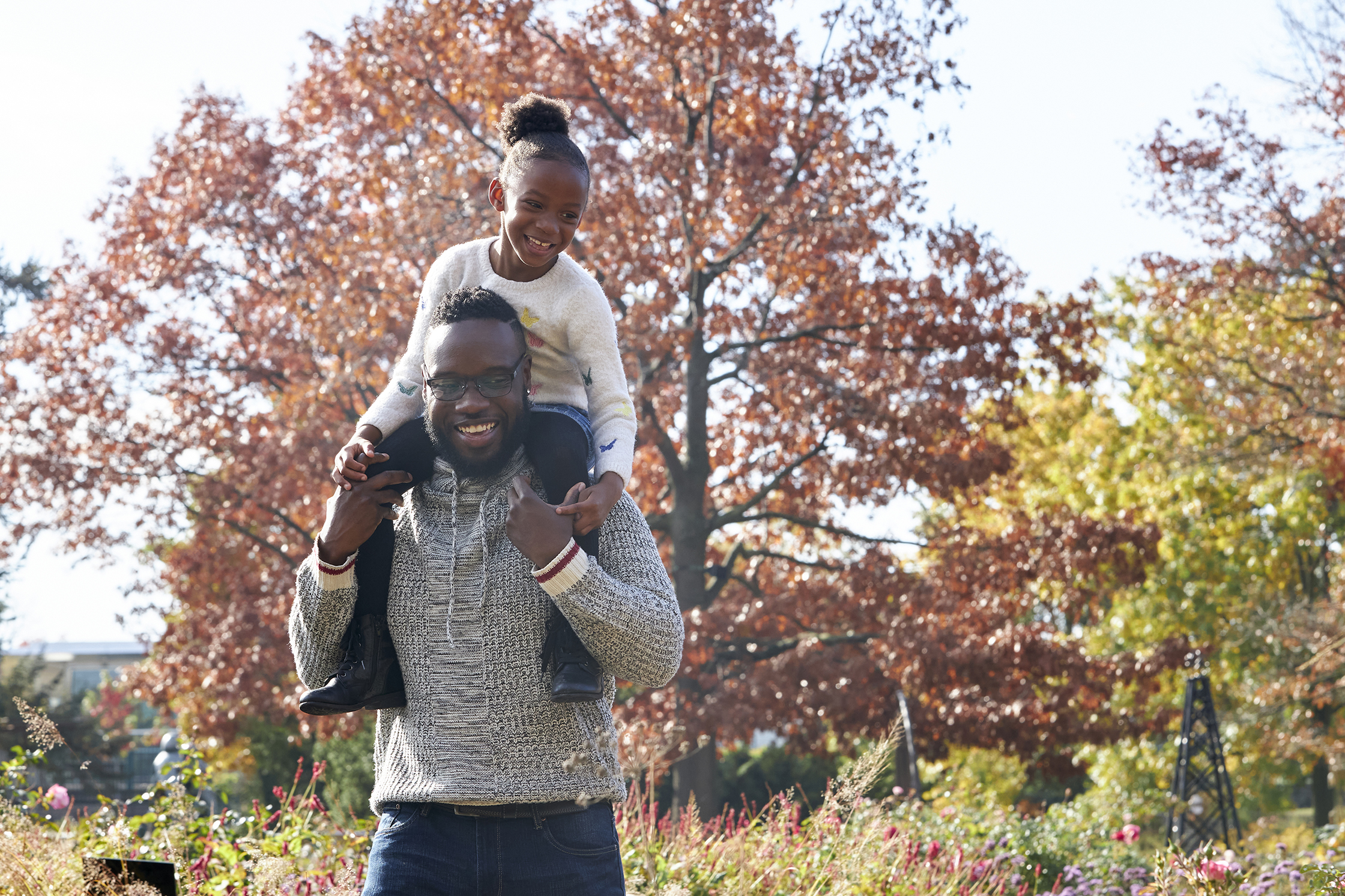 Father carrying daughter on shoulders in fall