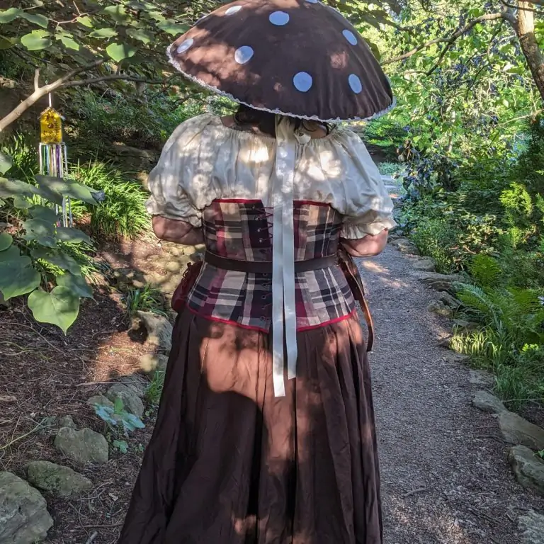person in a fantasy outfit with mushroom hat walking through rock garden
