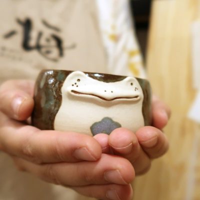 Frog pot meii studio Hands holding small pot shaped like a frog