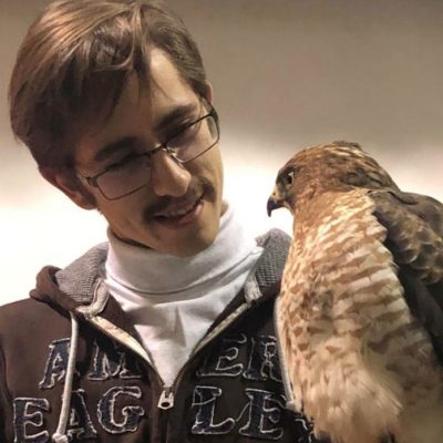 Man in glasses and a hoodie holding a hawk