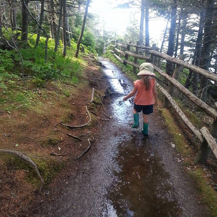 Young child walking down a muddy trail towards the water