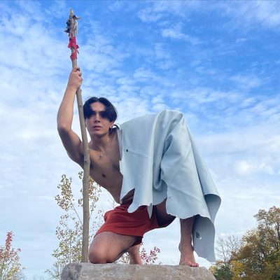 Montana summers Montana Summers crouched atop a large rock in a natural space, posing with a large walking stick