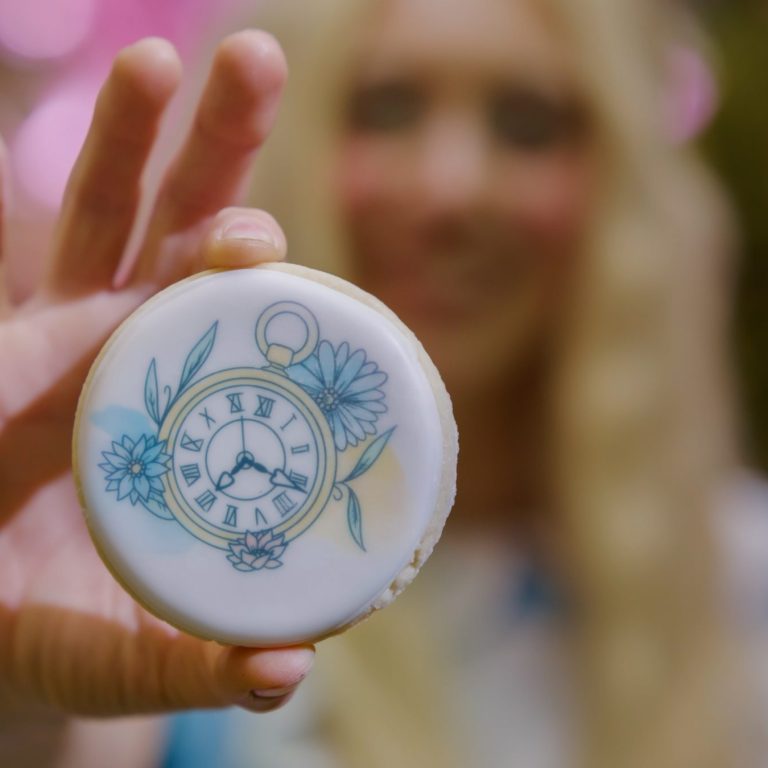 Alice character holding up a sugar cookie with custom clock design