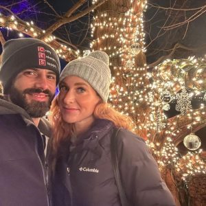 #RBGWinterWonders-MatthewShortt-DawnRedwood Selfie of two people in front of a Dawn Redwood tree decorated with Bright Christmas lights