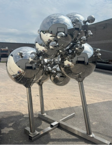 Dan Lawrie International Sculpture Collection - Spheres of Influence -Ron Baird Spheres of Influence - a reflective silver sculpture made of interconnected spheres stands on four metal legs
