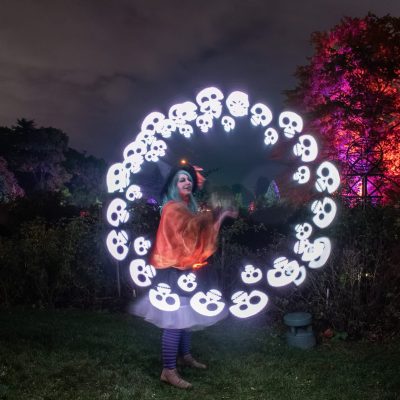 UP_RBG 2023_Pumpkin Trail_LL16835 Performer dressed in witch costume spins a skull shaped projection