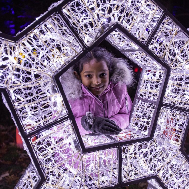 Young girl posing in the centre of a snowflake light installation