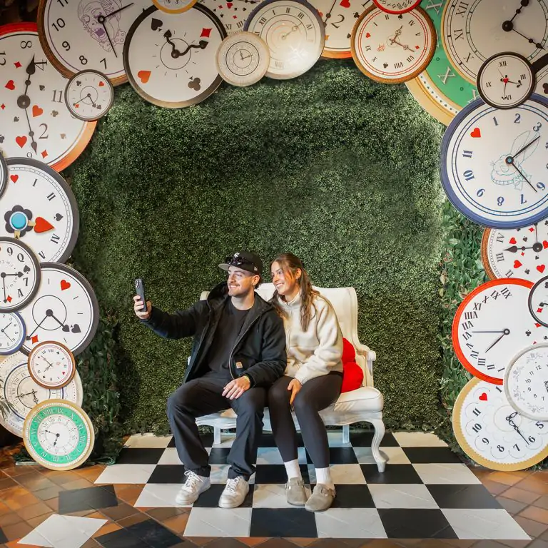 couple posing with a photo op surrounded by clocks on a checkerboard floor