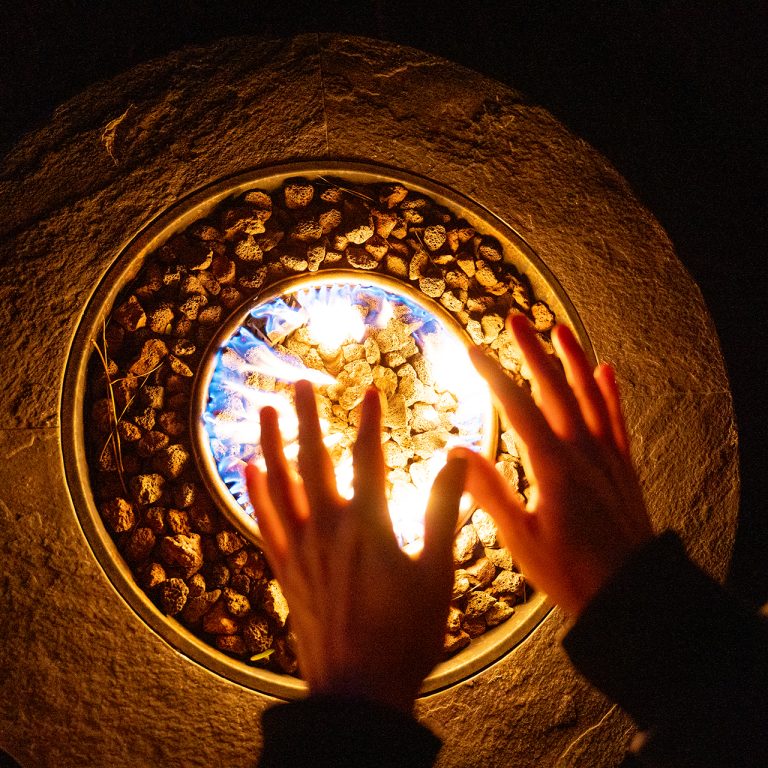 hands warming over a propane firepit