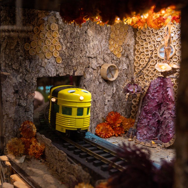 A small yellow train car moves into a small room made of wooden materials