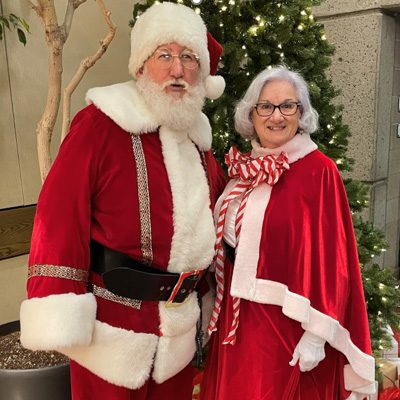 Santa and Mrs Claus posing by a christmas tree