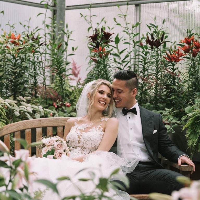 Bride & Groom on Bench surrounded by flowers