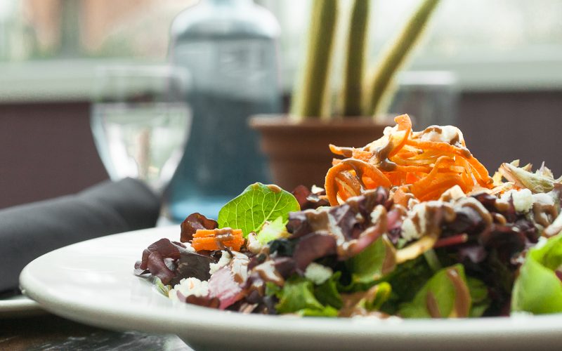 Salad - Greenhouse Cafe close up of a leafy green salad with spiralized carrots on top
