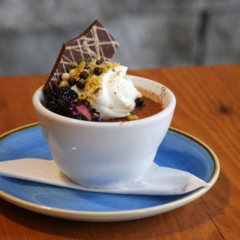 Chocolate Pot de Crème dessert, garnished with whipped cream, blackberries and a piece of chocolate