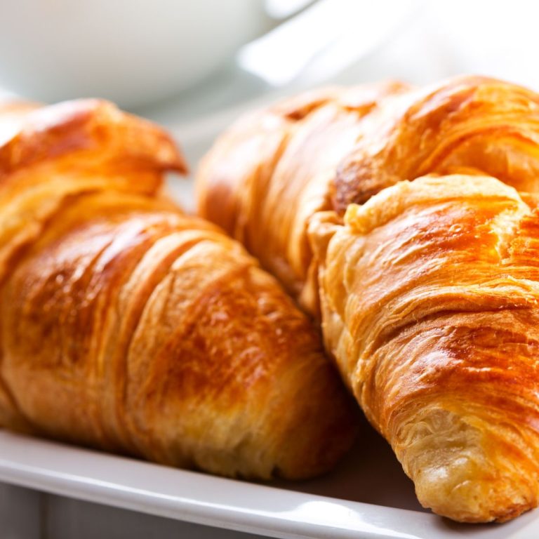 two butter croissants on a square white plate