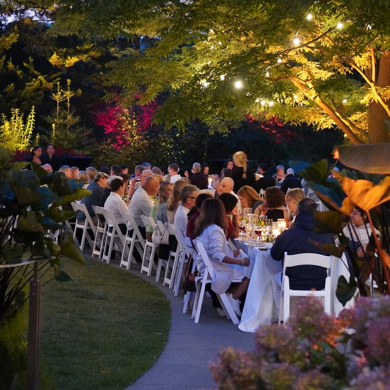 long table filled with guests winding along pathways in the upper level at rock garden at dusk