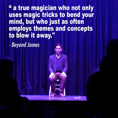 factory_social3 Nick wallace sitting on a stool on stage with a quote in text: "a true magician who not only uses magic tricks to bend your mind, but who just as often employs themselves and concepts to blow it away" - Beyond James