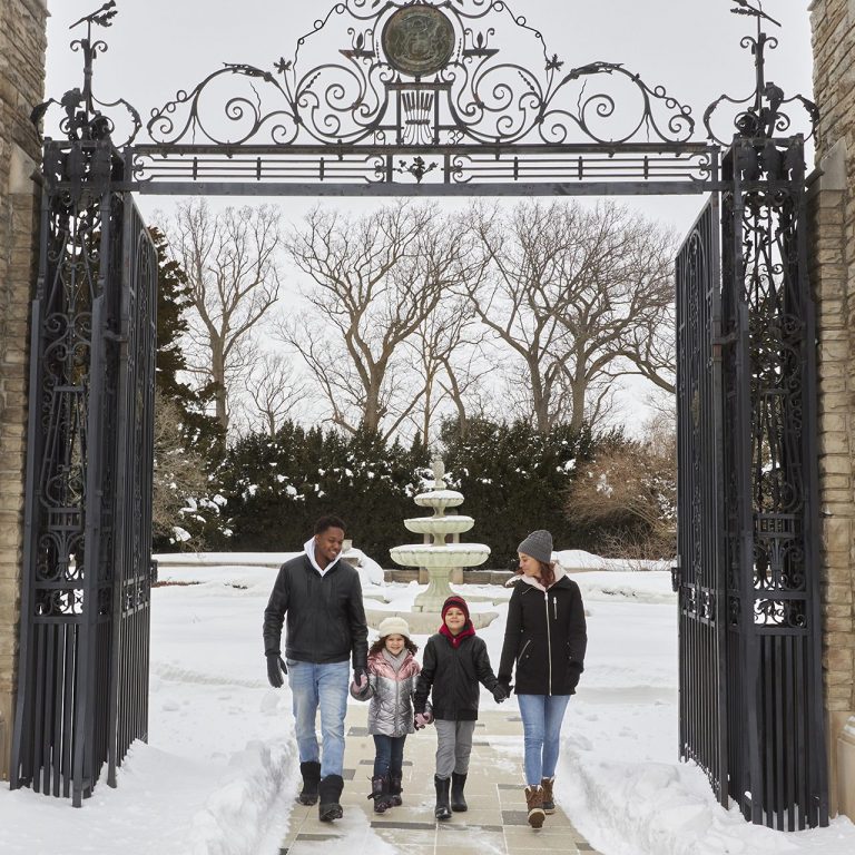 Family of four walking through Hendrie Park Gates in winter