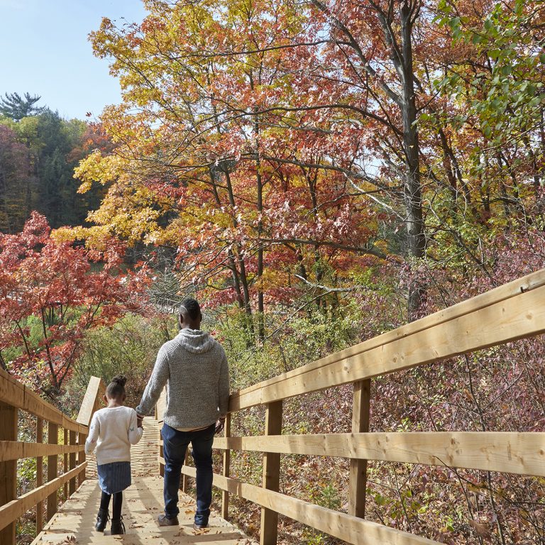 father and daughter hiking on staircase along boardwalk fall