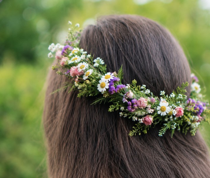 flower crown Person with long brown hair wearing a flower crown made from small, wildflower-like flowers and greenery