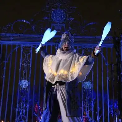 stilt walker dressed as jack frost with light-up juggling pins